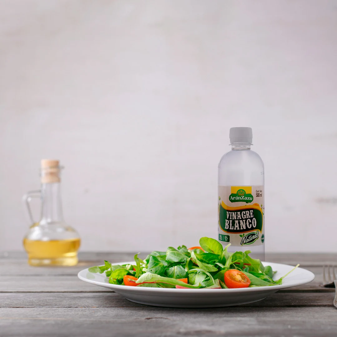 Vinagre blanco Aránzazu de 500 ml junto a una ensalada; foto de referencia de la marca